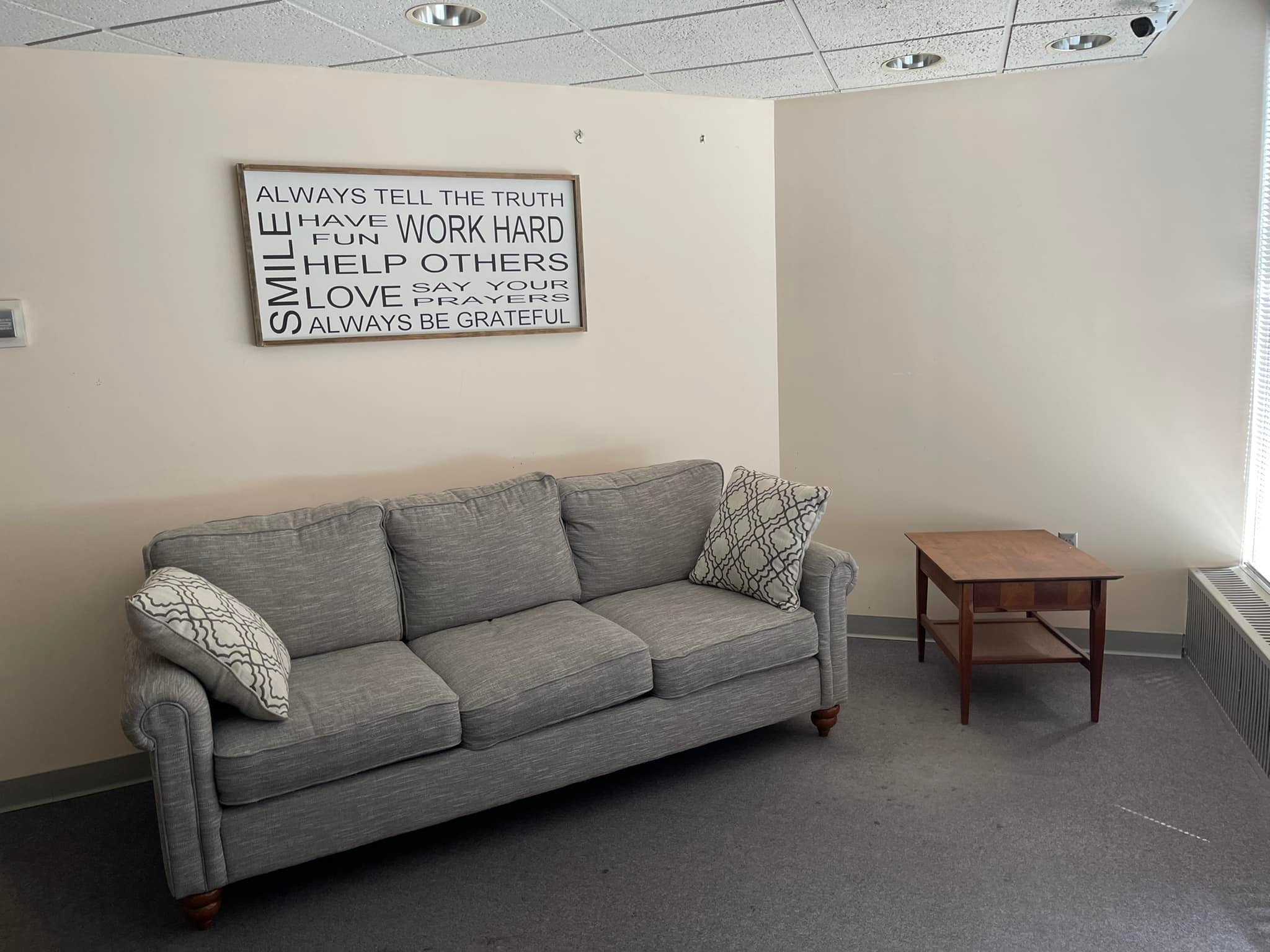 A clean room with a couch, a picture, and an end table