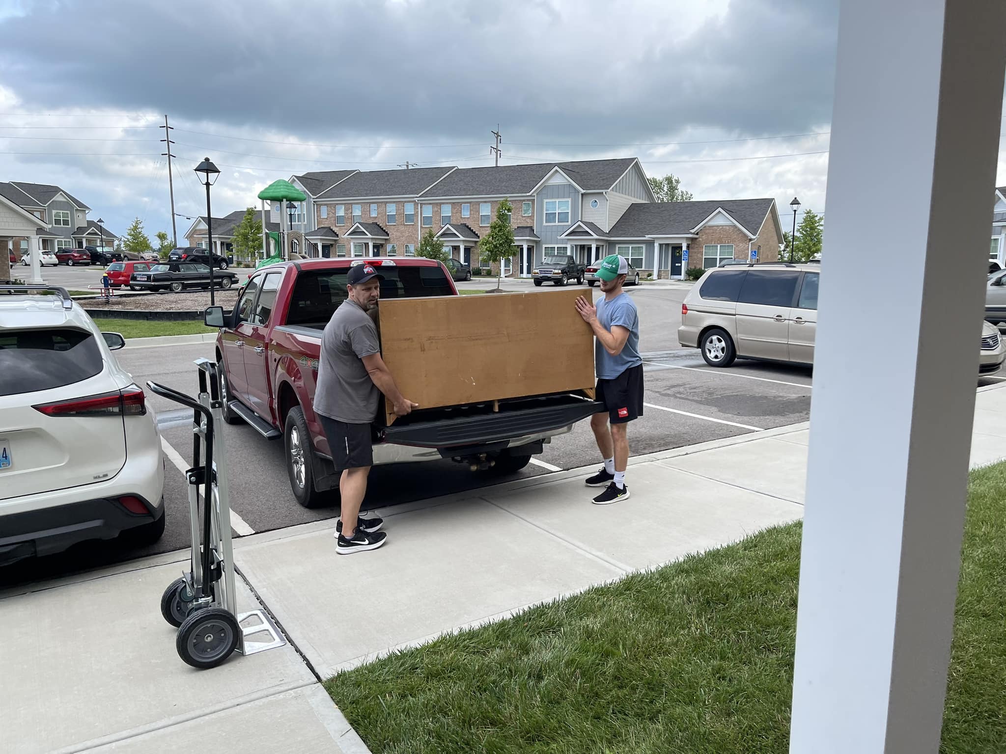 Two men moving a large piece of wooden furniture